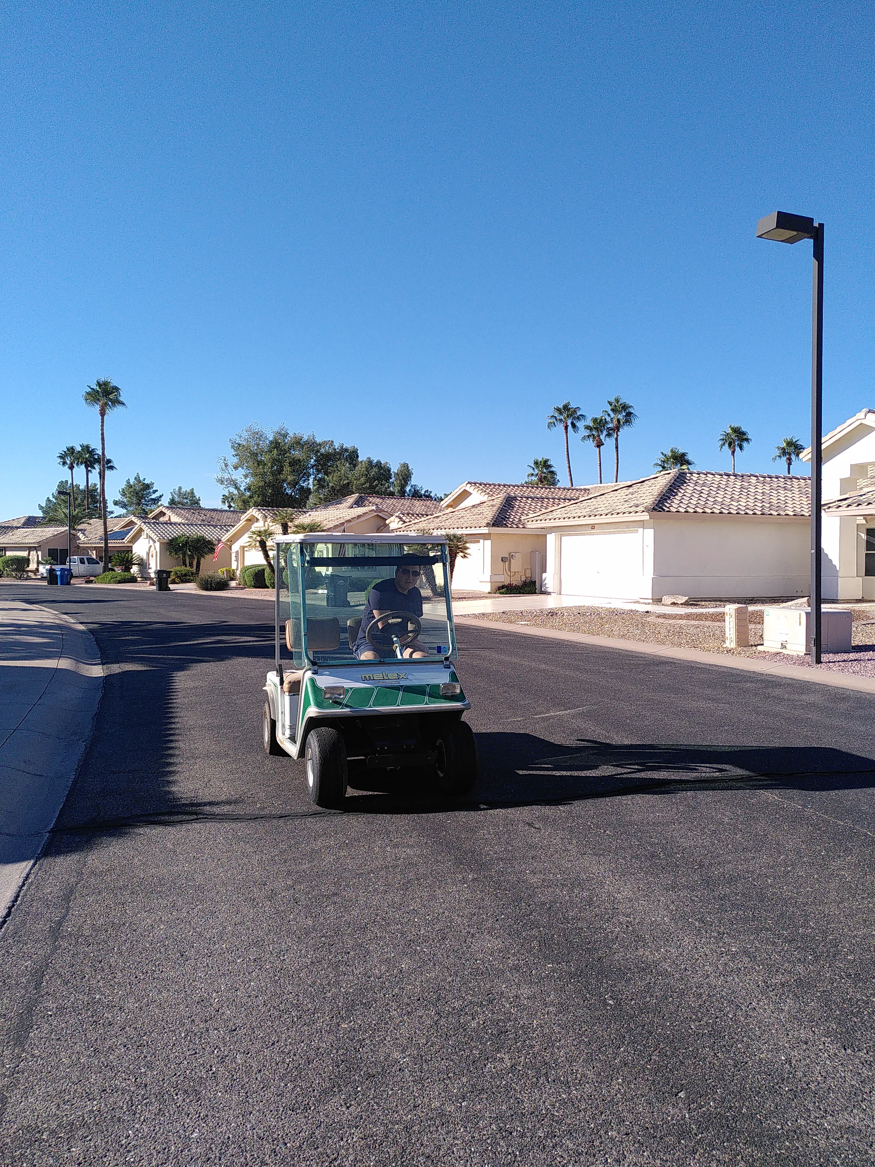 A man driving a golf cart towards the camera