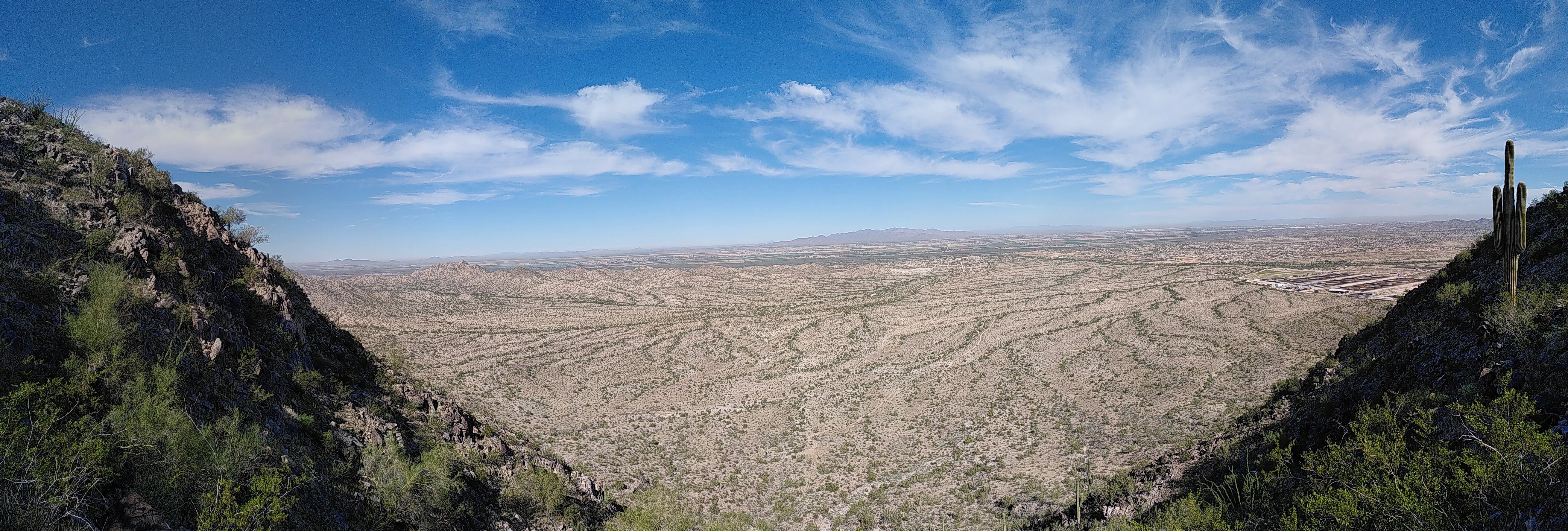 A view of the desert, with rocks framing either sides and a cactus visible on the right