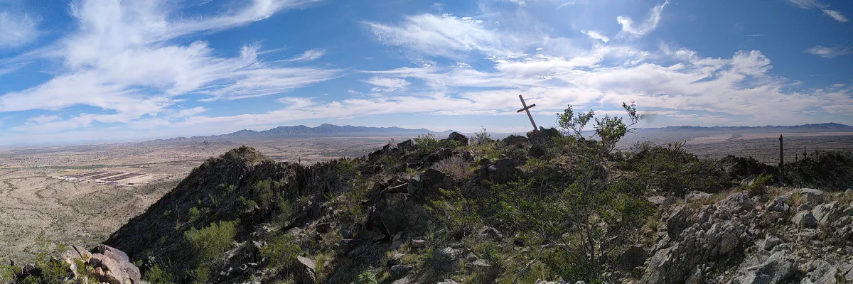 The view from the top of a mountain, with a large cross mounted in the ground