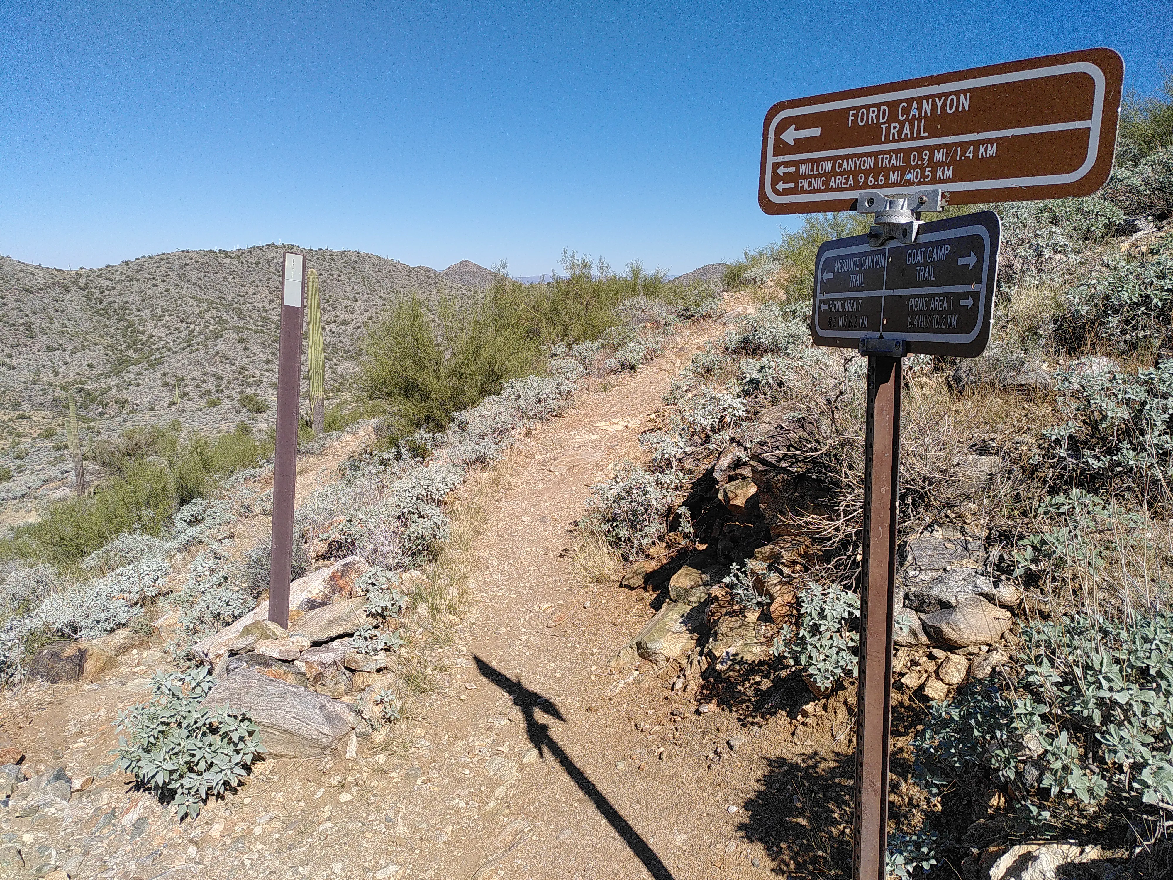 Signs at a trail fork, detailing various routes and distances