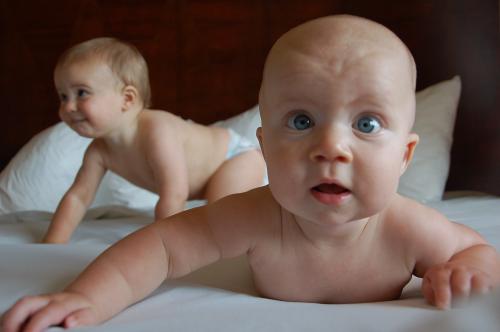 Two babies laying on a bed