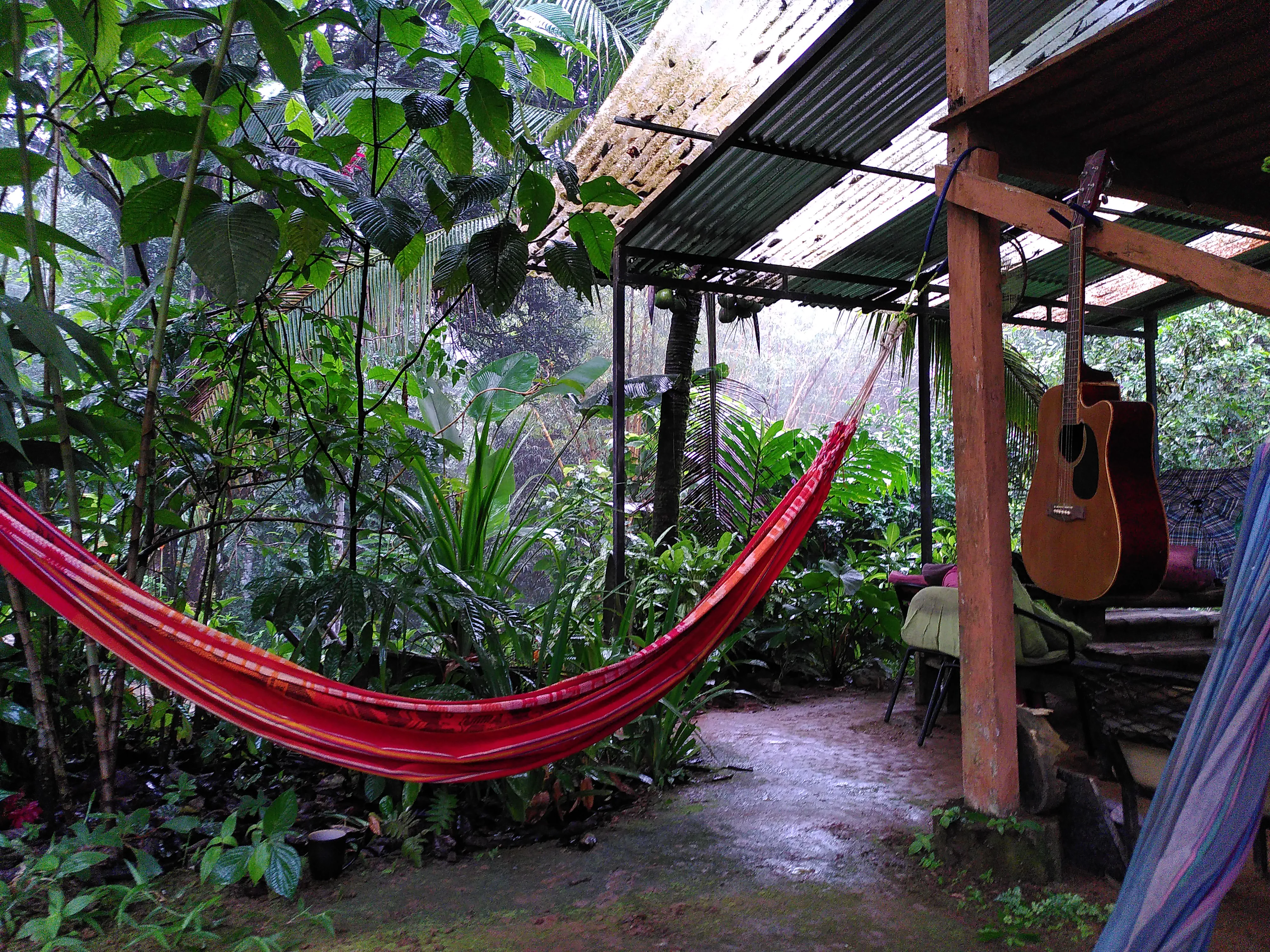 A hammock attached to a wooden structure, with heavy rainfall visible in the background