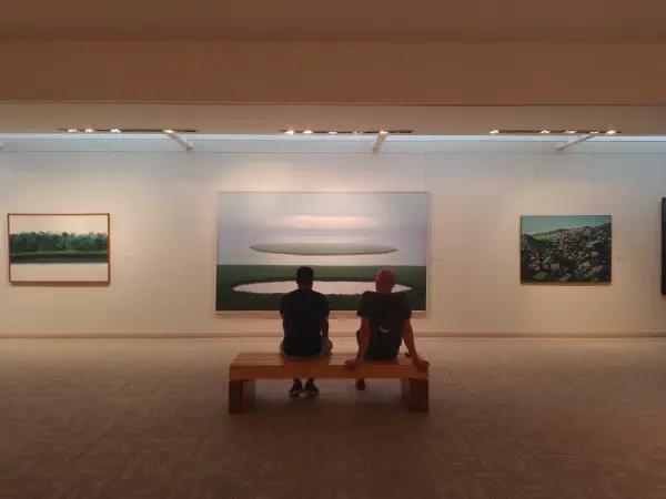 A forest with a circular lake in it alongside the sea with a circular island in it