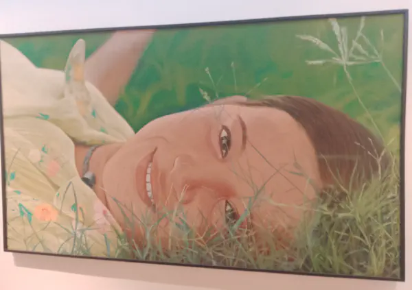 A woman lays in the grass, smiling at the viewer