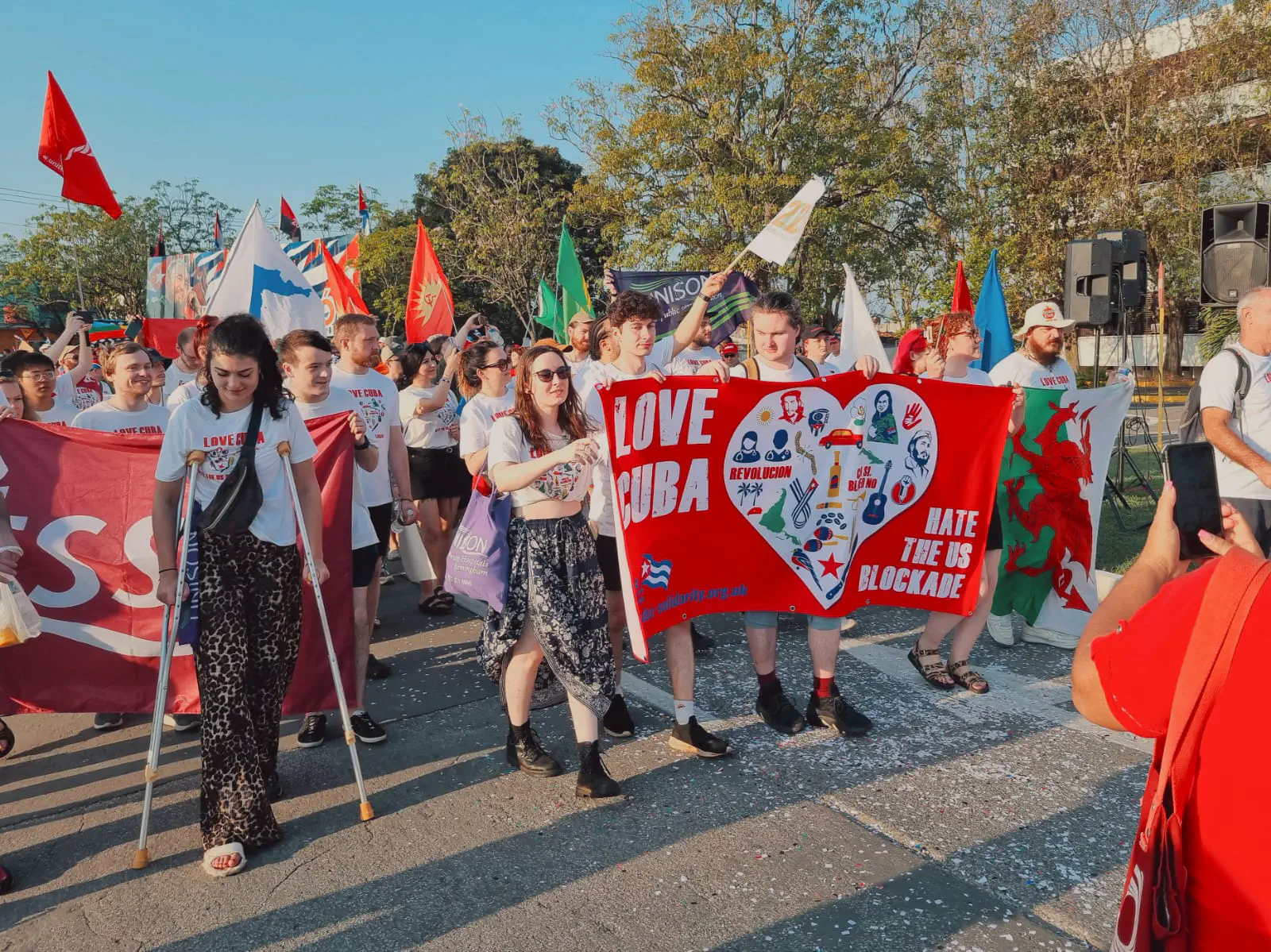A large group marching through the streets carrying a banner that reads ‘love Cuba, hate the US blockade’
