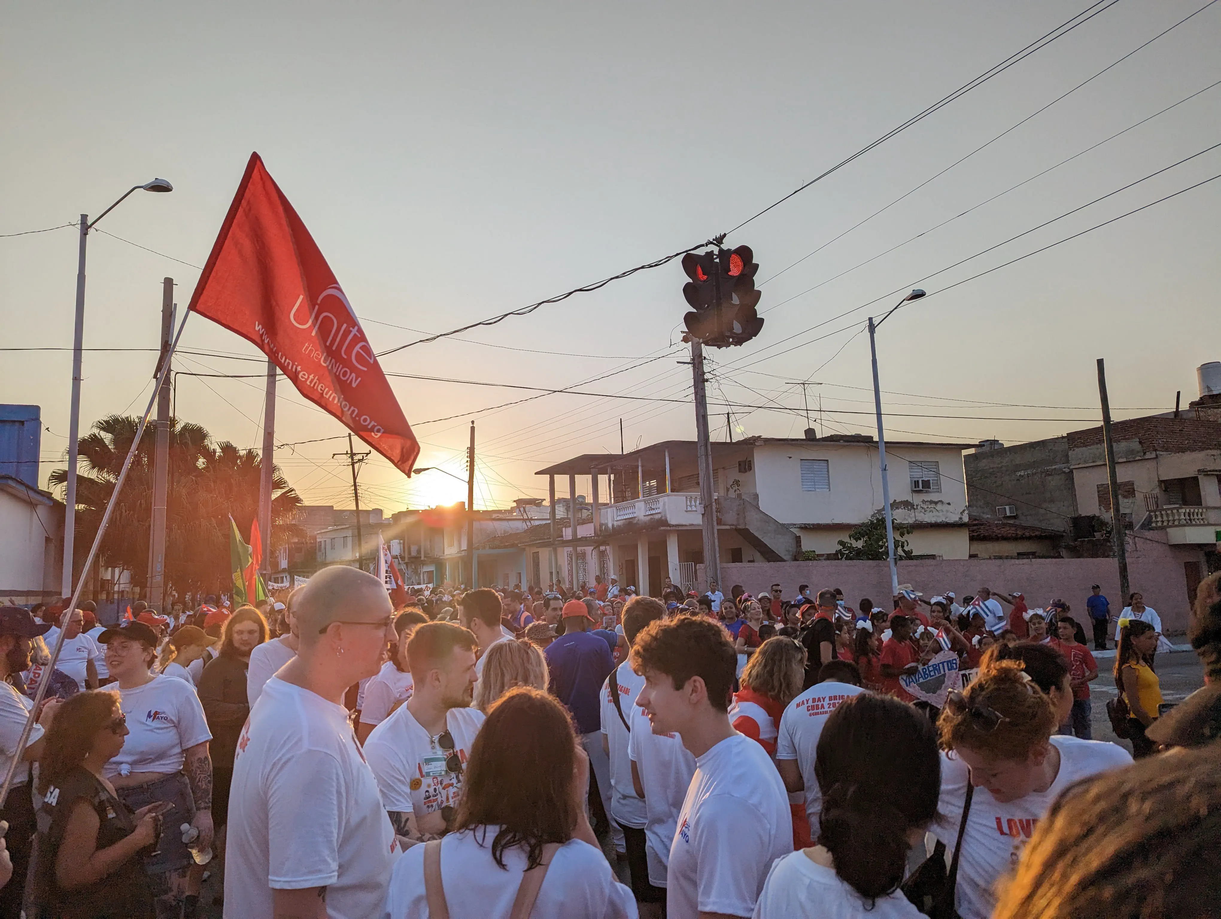 The sun rising over a large street crowd, with union flags flying