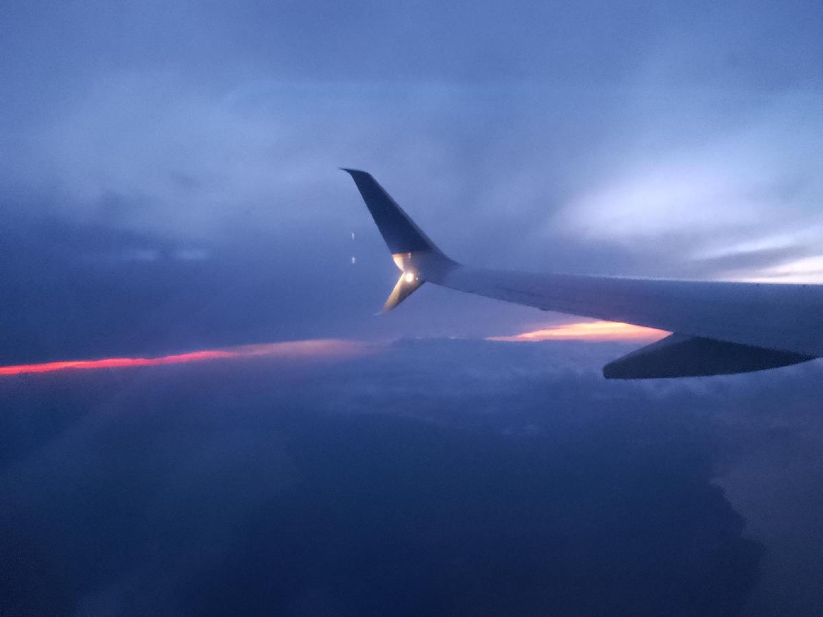 The wing of an aeroplane seen through the window, looking out over the sun rising over Cuba