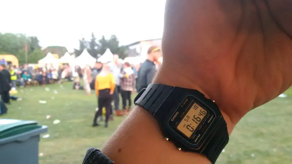 My watch showing that it is midnight, as people party in the sunshine in the background