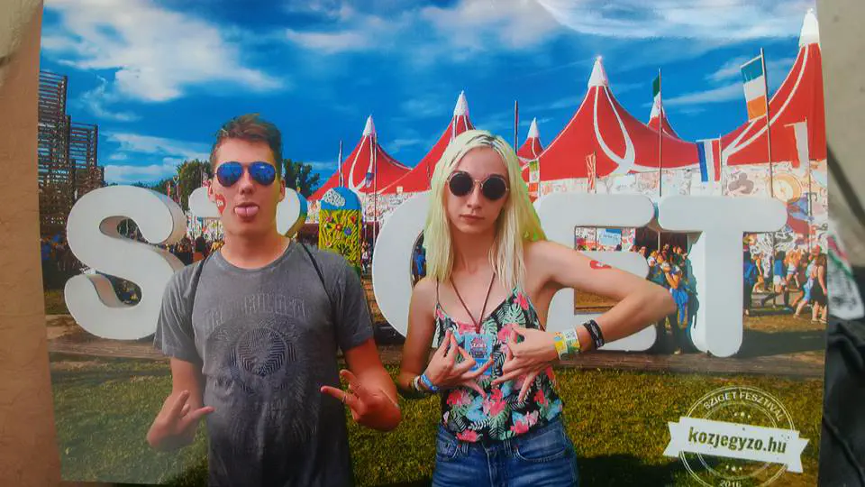 Two people standing in front of a free-standing sign reading ‘Sziget’