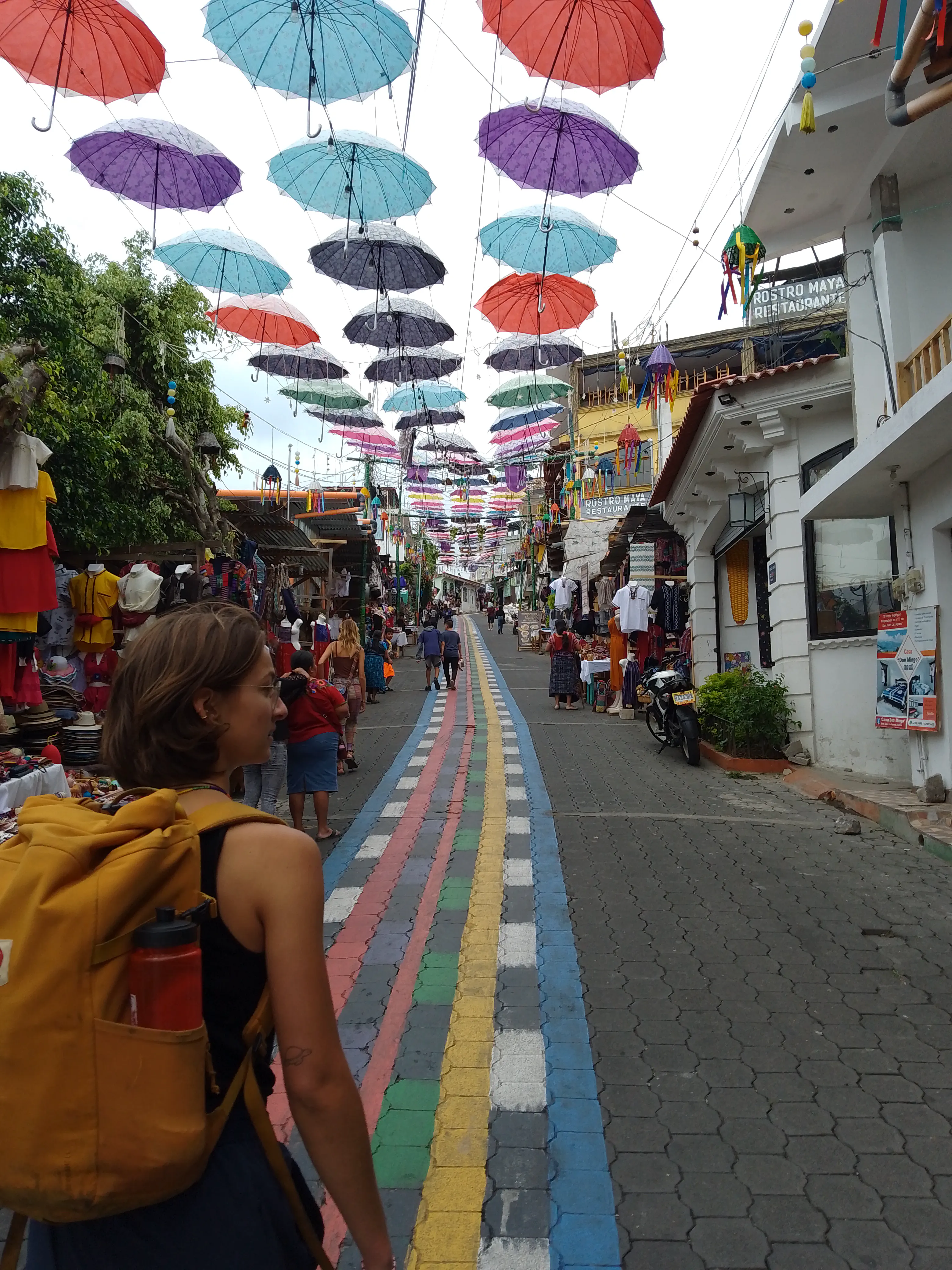 A woman walking ahead along an uphil street decked out with flags