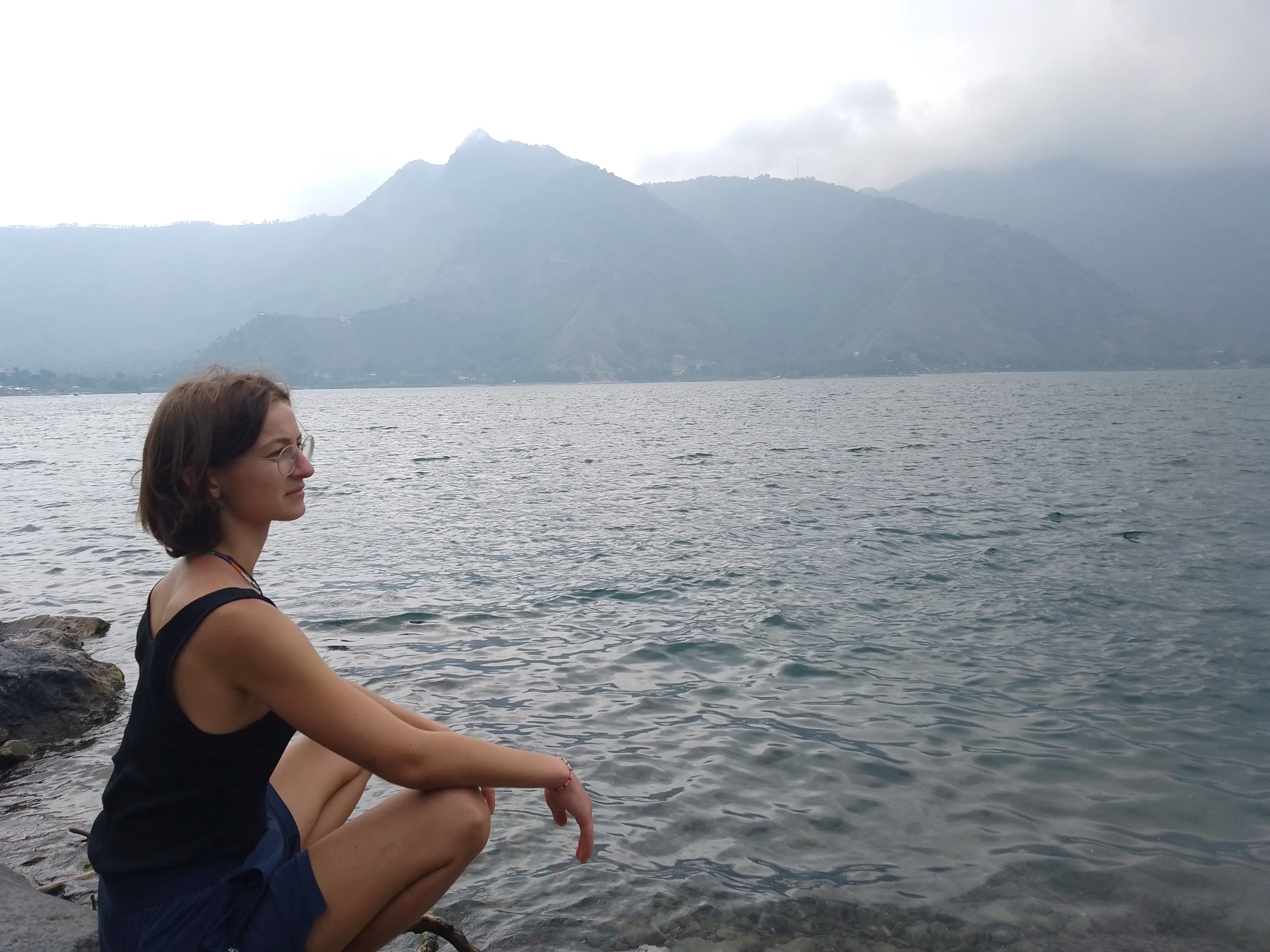 A woman sitting on a rock, looking out over a lake