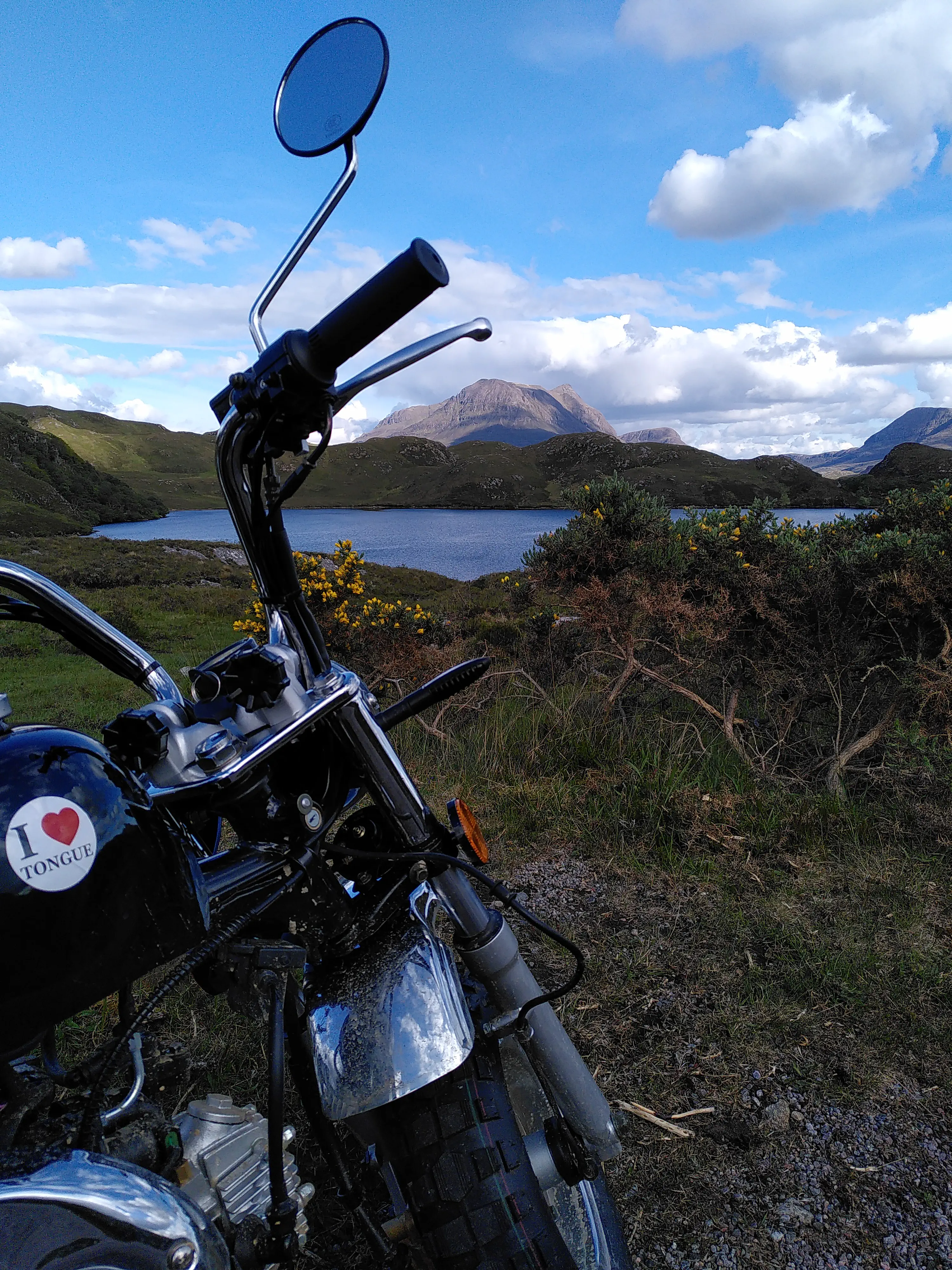 A monkey bike in front of a mountain, with a sticker reading ‘I love Tongue’
