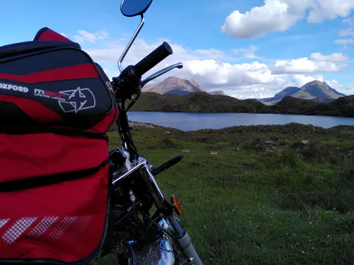 A monkey bike in the foreground, dwarfed by mountains in the background
