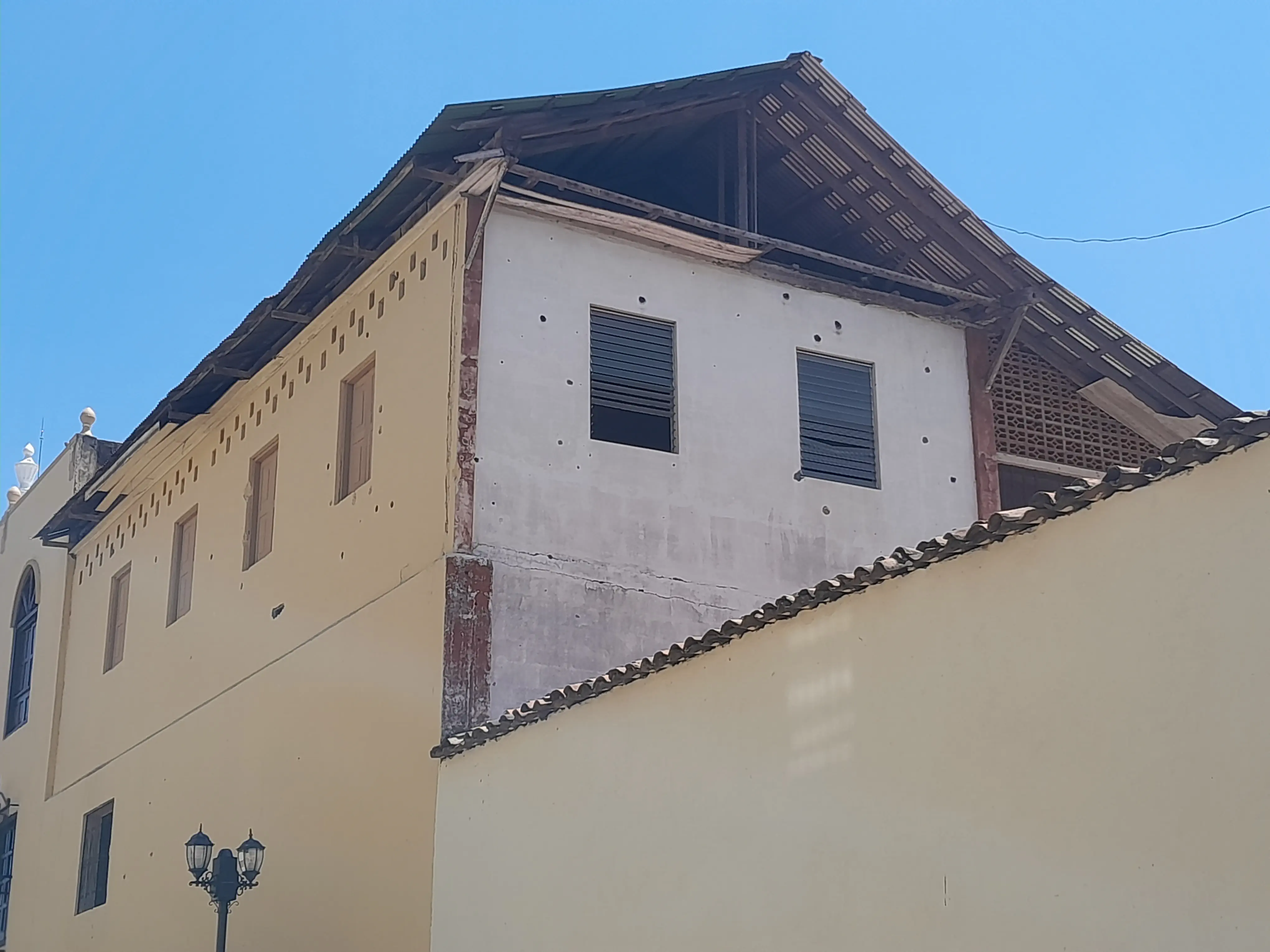 A building, its walls dotted with bullet holes