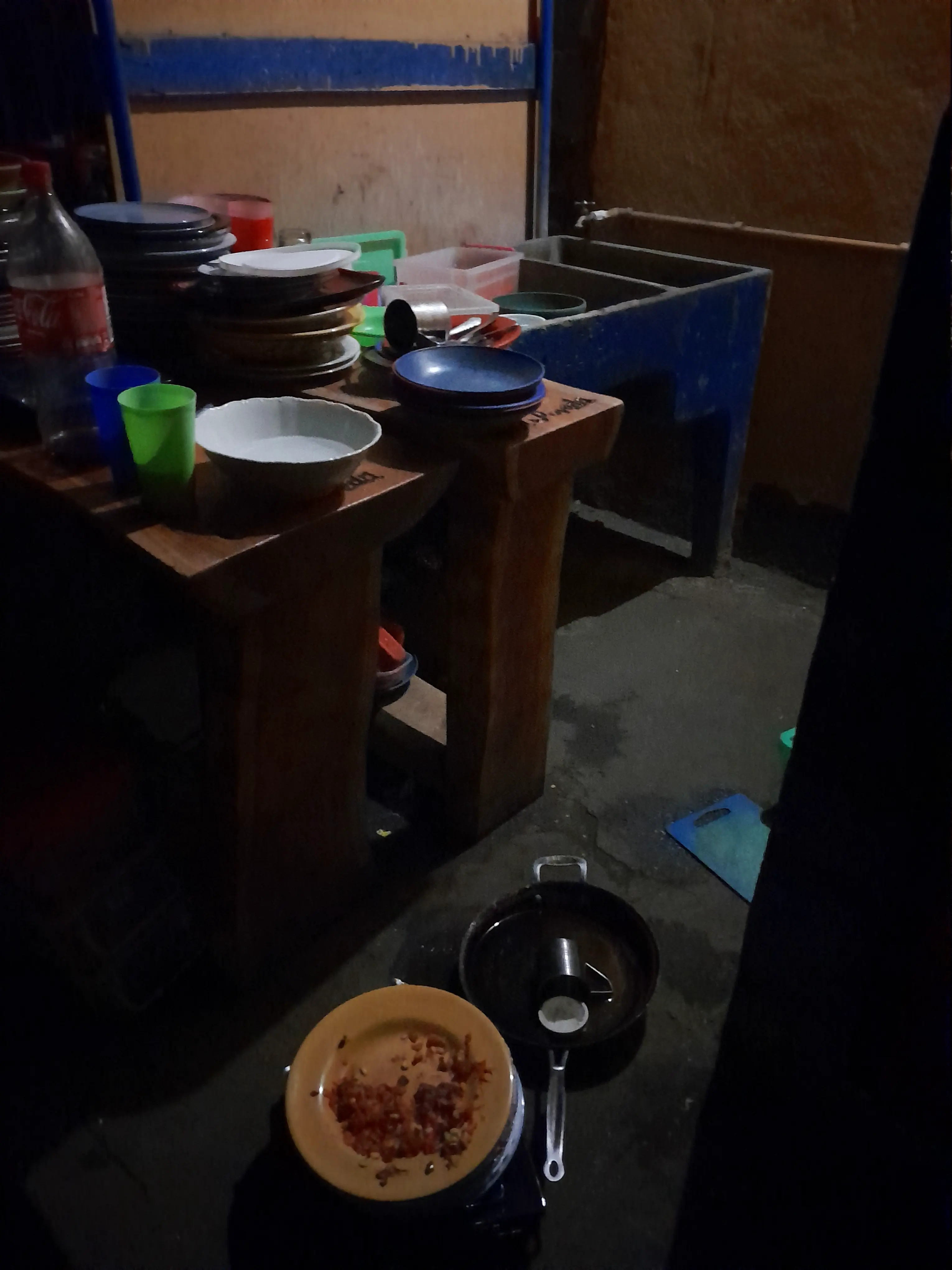 A kitchen area piled high with dirty dishes, including on the floor