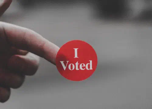 Hand with red sticker reading 'I voted'