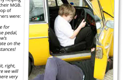 Young boy in drivers seat of car, with man laying underneath
