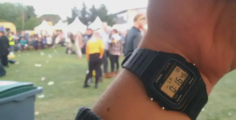 A watch showing the time to be 00:14, with a sunlit field in the background