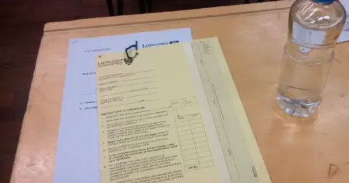 An exam paper on a desk with a bottle of 'water' beside it