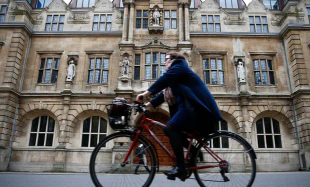 A cyclist riding in front of an Oxford University building