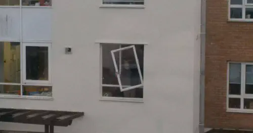 A window partially hanging from its frame