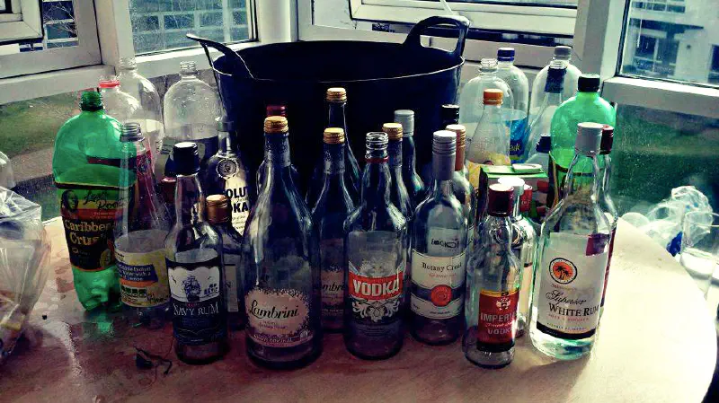 Large bin surrounded by bottles of alcohol